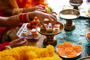 Indian women in traditional clothing preparing sweets and decorations for a multi-festival celebration