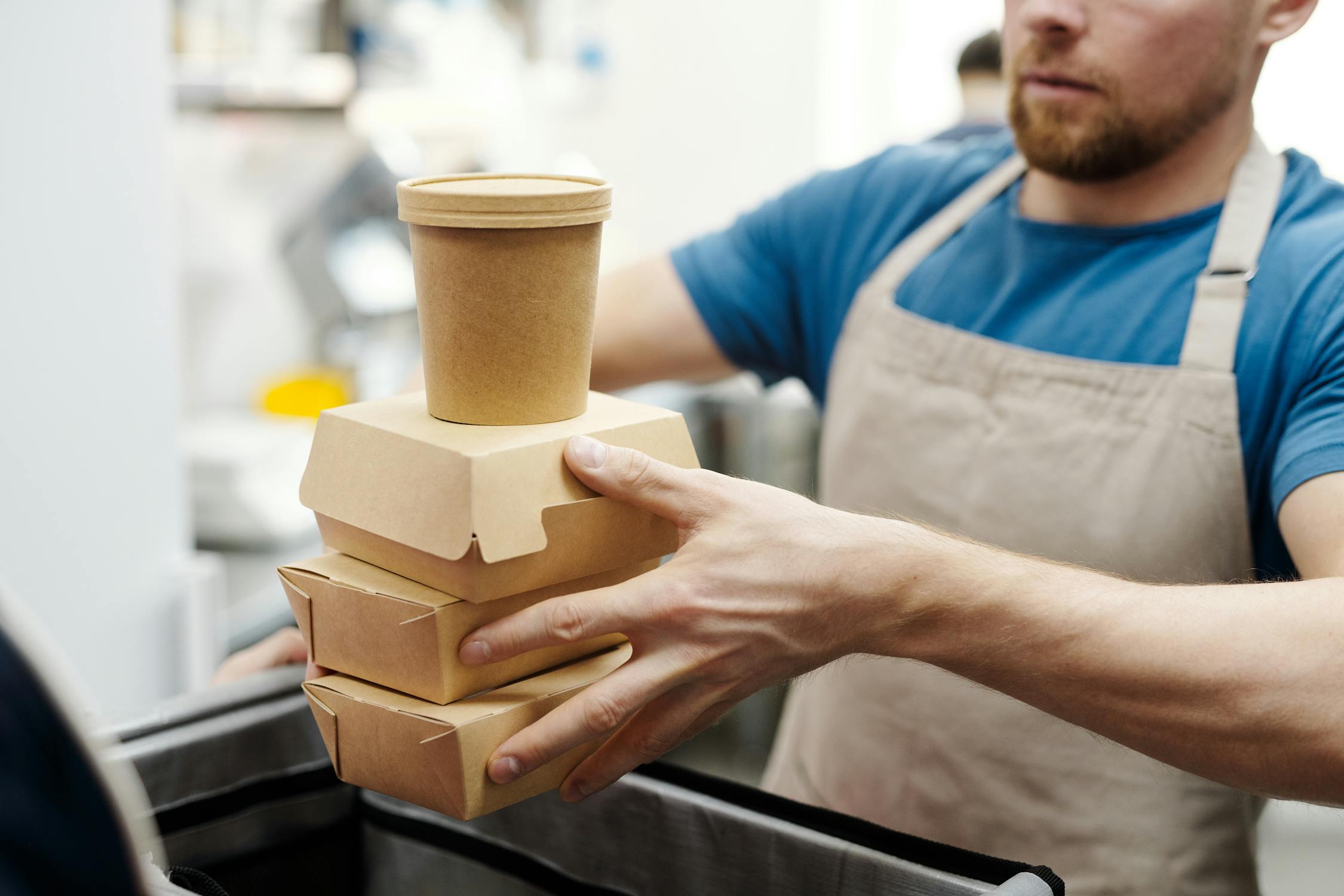 Restaurant worker stacking compostable food containers for takeaway delivery