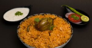 Hyderabadi mutton biryani served with raita and onion garnish, a centrepiece of Eid al-Adha catering in India