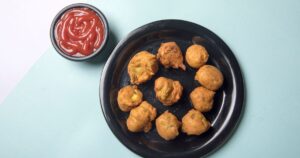 Plate of crispy hot Indian pakoras with ketchup, the classic monsoon comfort food special for a restaurant menu