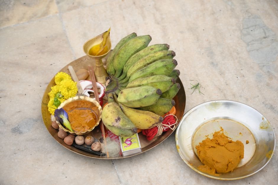 Brass puja thali with green bananas, marigold flowers, turmeric and vermilion arranged as Durga Puja offerings